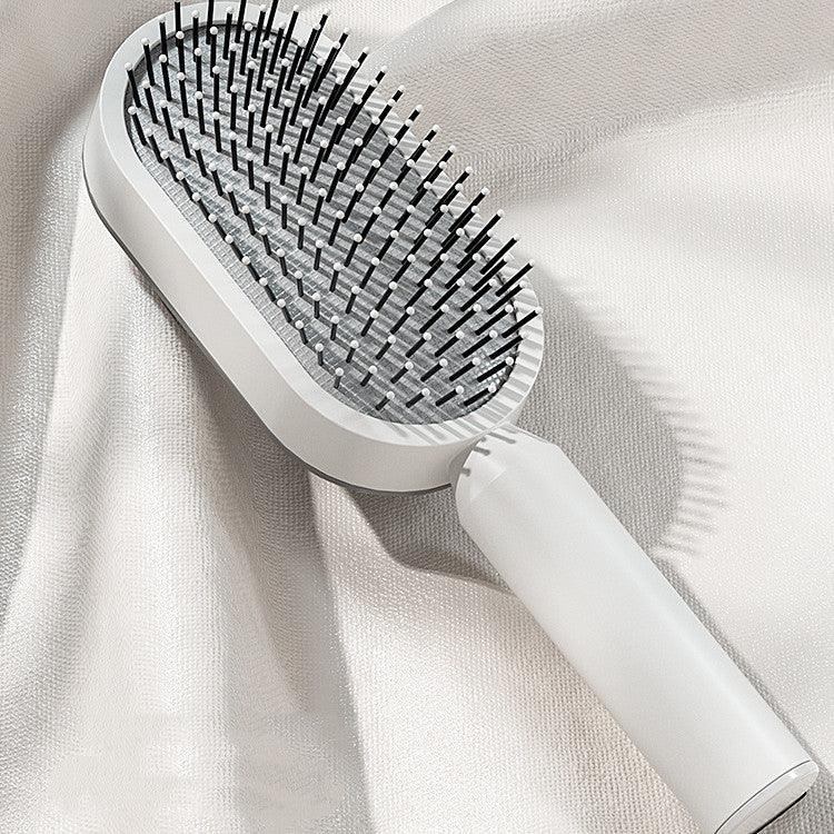 White electric scalp massager and hairbrush with black bristles on a soft fabric background